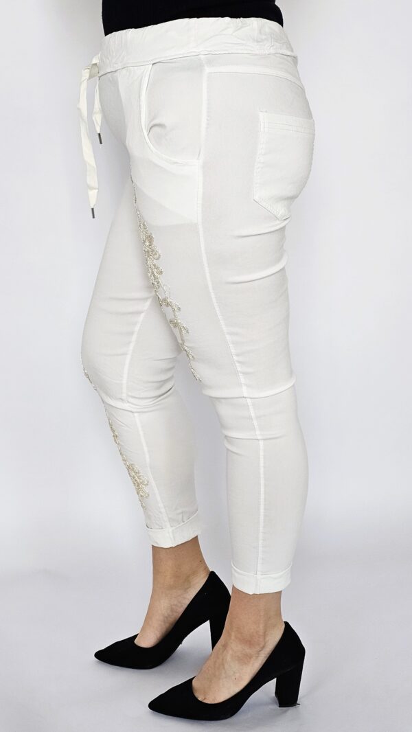 Spodnie gnieciuchy z haftowanym kwiatem na przodzie - białe